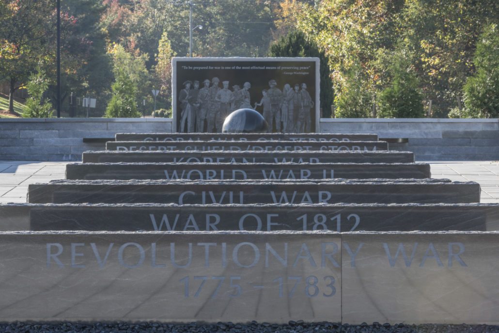 The Stafford County Armed Services Memorial, with the names of nine wars cut into ascending granite steps and a carved panel of service members behind