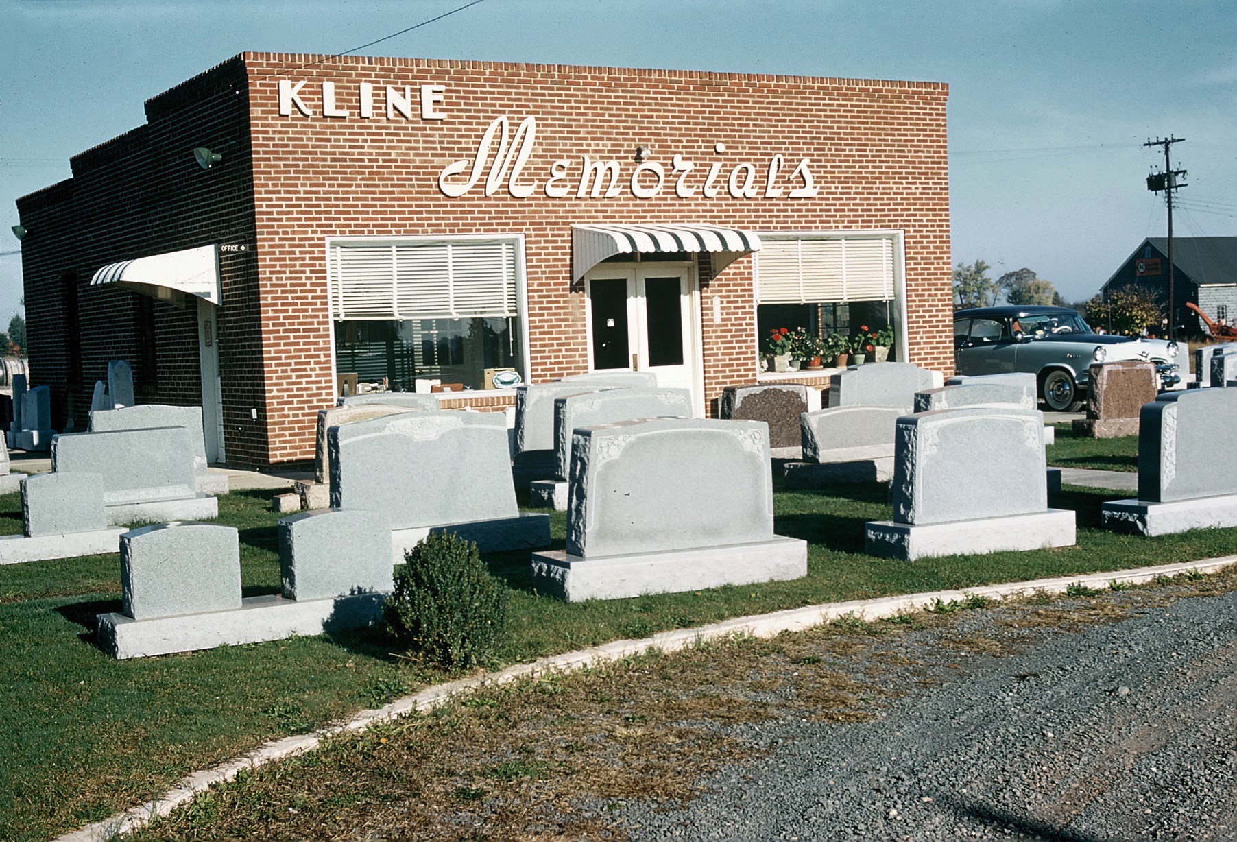 The Kline Memorials brick building on Centreville Road in the 1950s, with a script sign and monuments displayed on the grass
