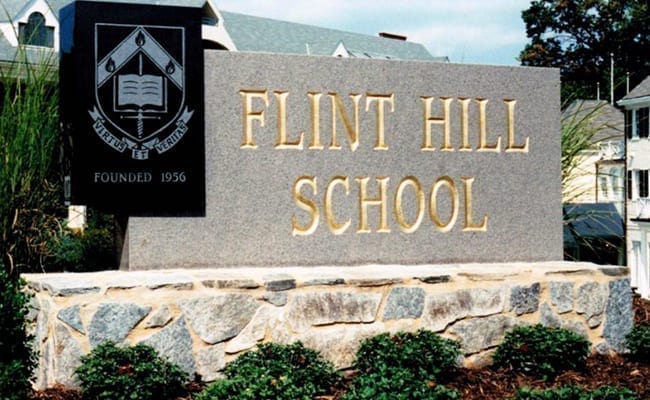 Granite entrance sign with gold leaf lettering on a fieldstone base